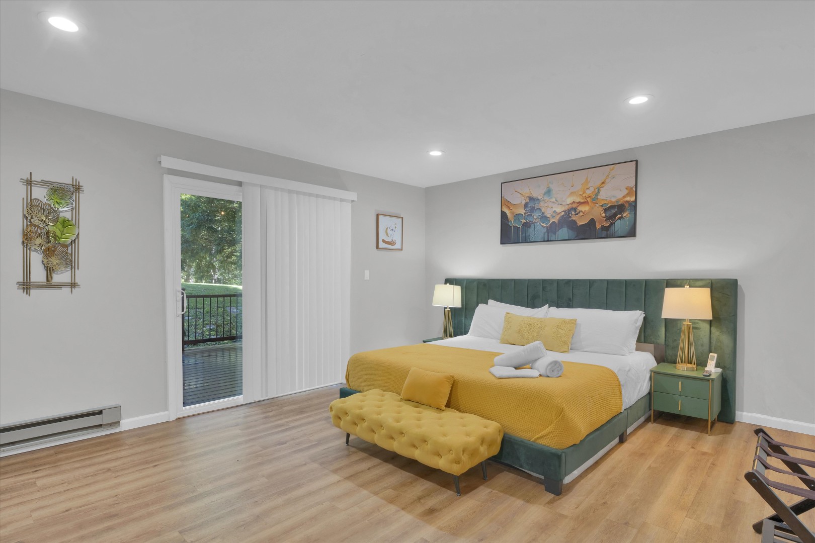 Tranquil bedroom retreat with a plush king bed, mustard accent bench, and deck access.