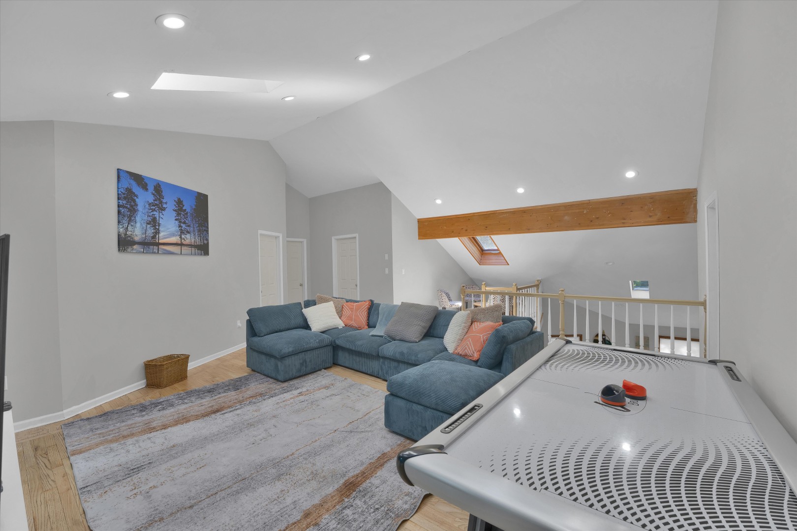 Spacious upper lounge featuring a plush sectional, air hockey table, and vaulted ceilings with skylights