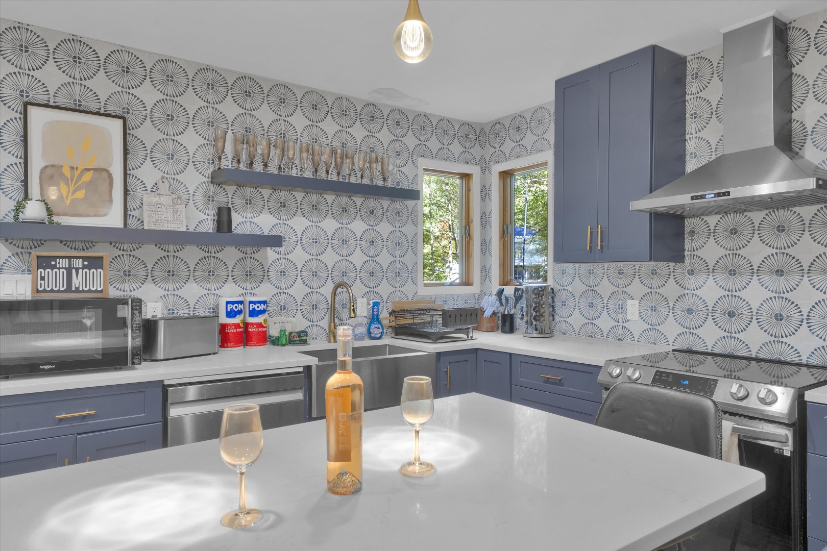 Modern chef’s kitchen featuring sleek blue cabinetry, a large prep island with wine seating, and an eye-catching tile backsplash.