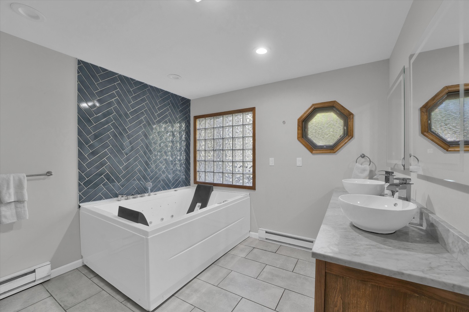 Spa-inspired primary bath equipped with a Jacuzzi tub, herringbone tile feature wall, and dual vanities.