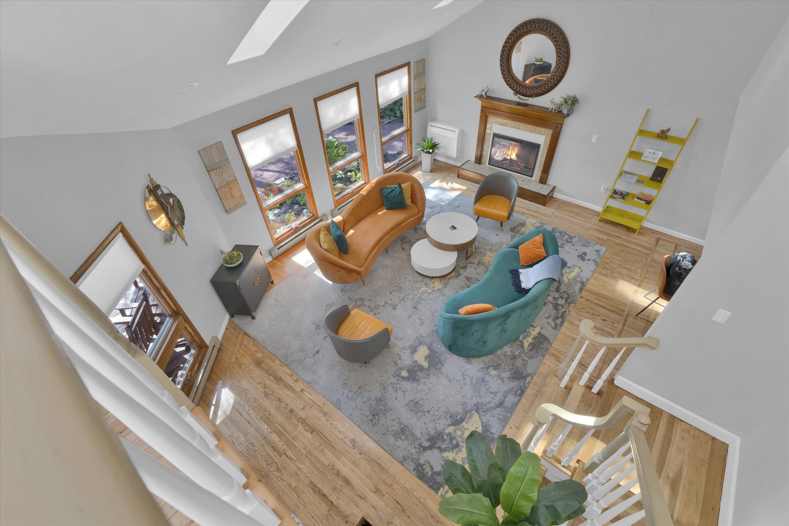 Overlooking the main floor - enjoy a vibrant, spacious seating area framed by rustic wood flooring and a cozy fireplace.