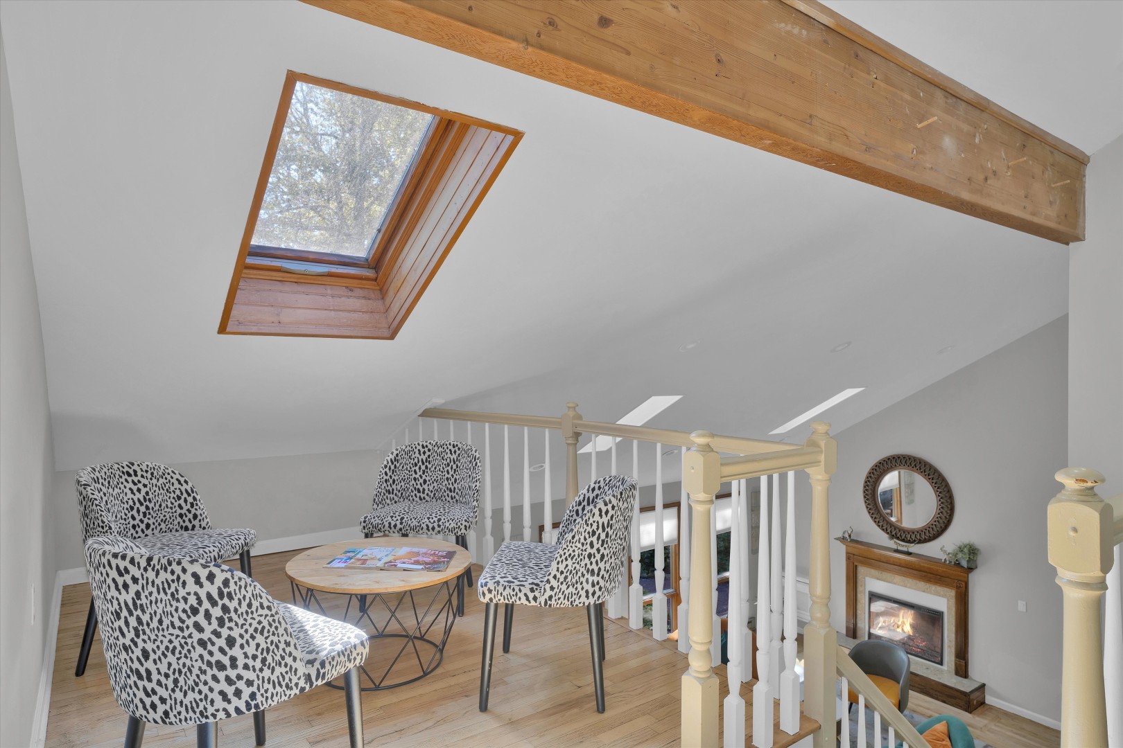 Airy loft overlook with soft seating and skylights framing peaceful forest views.