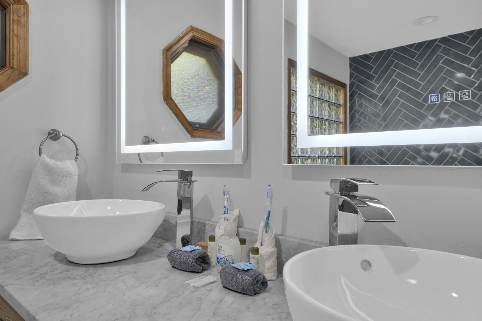 Sleek double vanity with modern vessel sinks and brightly back-lit LED accent mirrors.